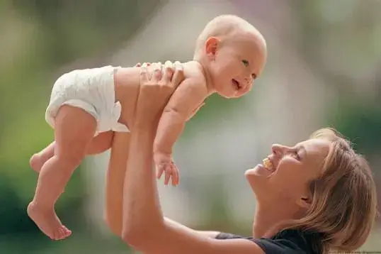 Woman joyfully holding her baby in the air, highlighting the importance of family planning and registering wills with a trusted Register of Wills service